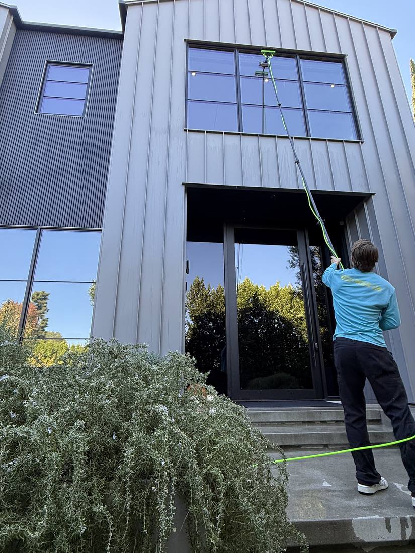 Technician cleaning second-story windows with a water-fed pole